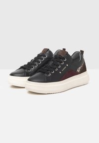 Sneaker in pelle nera con dettagli in suede bordeaux e marrone. Suola bianca, punta rotonda e design con lacci e occhielli in metallo.