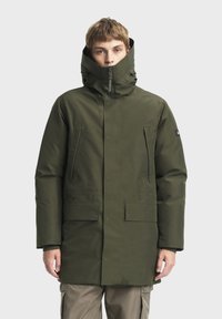 Parka verte en finition mate, dotée d'un col haut, d'une fermeture éclair, de poches latérales et d'une forme rectangulaire pour la chaleur et la protection.