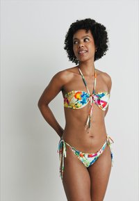 Bikini komplekts ar krāsainu ziedu rakstu; bez plecu siksnām, ar sasienamu augšdaļu un atbilstošām zemu vidukļa apakšdaļām ar sānu sasiešanu, izgatavots no gludas auduma.