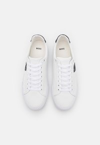 Baskets en cuir blanc avec des accents noirs, dotées d'un design à lacets, d'une semelle en caoutchouc et d'un logo embossé sur la languette et le côté.