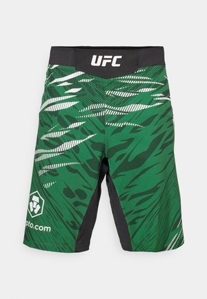Green and black athletic shorts featuring a bold, abstract pattern with diagonal stripes and a UFC logo on the waistband and side.