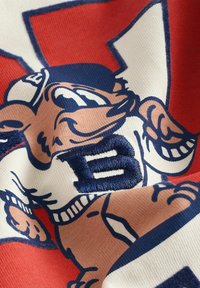 Tessuto rosso con stampa di personaggi dei cartoni animati. Presenta un ricamo blu scuro con la lettera "B" e dettagli dell'espressione e dell'abbigliamento del personaggio.