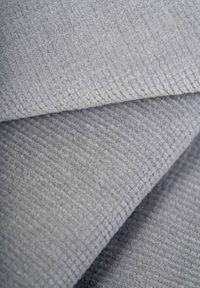 Gray textured fabric with a woven pattern, featuring a soft, fuzzy surface. The folds reveal subtle depth and dimension in the material.