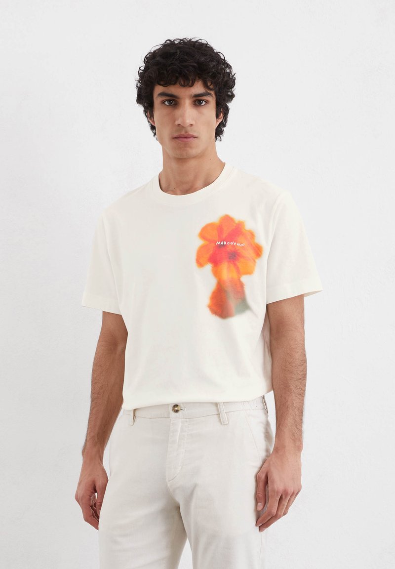 Cream-colored cotton t-shirt featuring a vibrant orange flower graphic on the left side. Short sleeves and a classic crew neckline.
