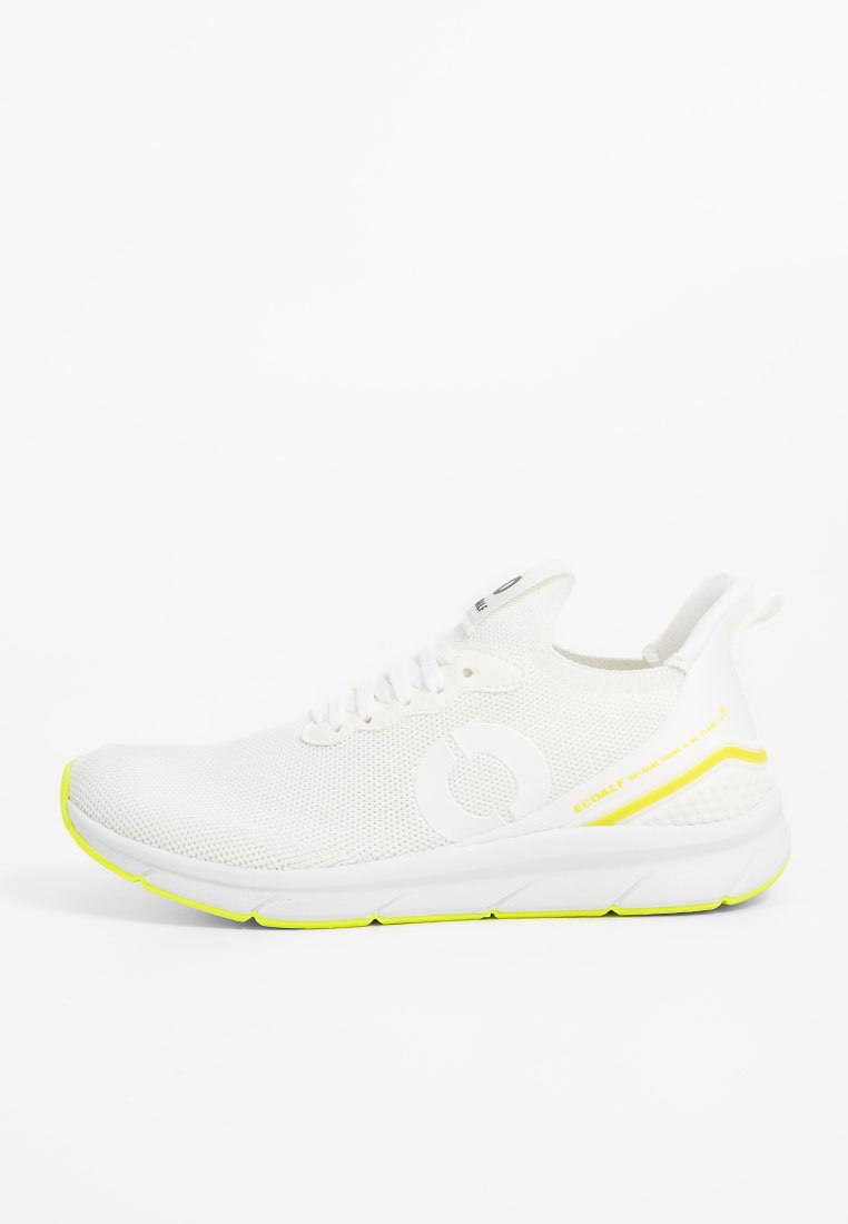 Deportivas de malla blanca transpirable con diseño de cordones, detalles amarillos en la suela y el talón, y un logo circular en el lateral.