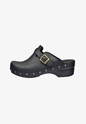 Zoccolo nero in pelle liscia con punta rotonda, dotato di una fibbia laterale e borchie decorative in ottone lungo il bordo inferiore.