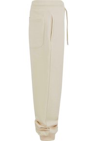 Pantalons de jogging beiges en tissu doux, avec une taille élastique, un cordon de serrage, des poches latérales et des poignets resserrés.