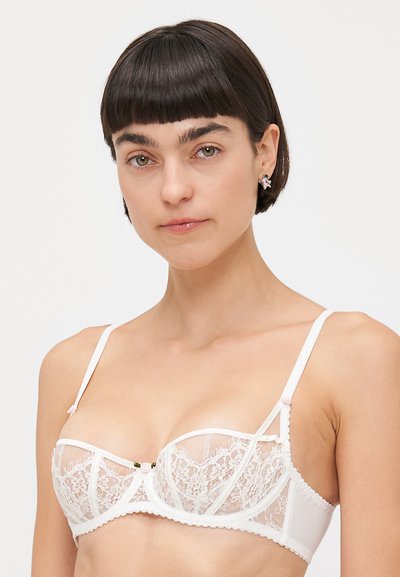 Witte kanten bh met doorschijnende cups, decoratieve naden en roze satijnen accenten. Verstelbare bandjes en bloemendetail in het midden van de voorkant.