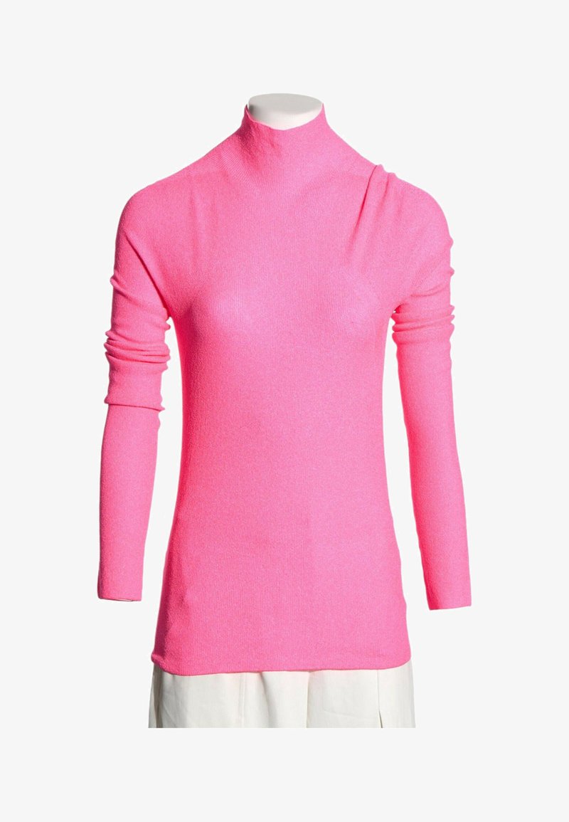 Pull col roulé rose vif à manches longues présenté sur un mannequin avec une jupe blanche.