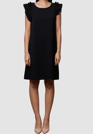 Vestido negro sin mangas con detalles de volantes en los hombros, de corte holgado que llega hasta la mitad del muslo. Textura de tela suave.