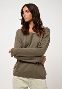 Maglione a maniche lunghe verde oliva realizzato in tessuto morbido, con scollo ampio e vestibilità comoda, con dettagli a coste sui polsini e sull'orlo.