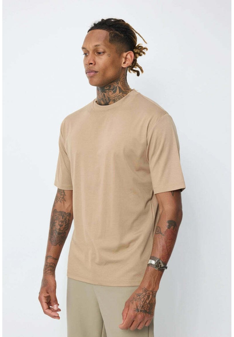 T-shirt beige à manches courtes avec col rond, fabriqué en tissu doux, présentant une coupe décontractée et une texture lisse.