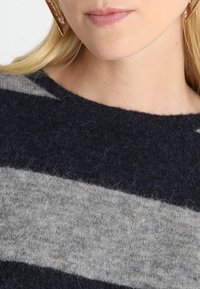 Marinblå och grå randig stickad tröja med mjuk textur och rund halsringning, som visar upp fina fibrer och en avslappnad design.