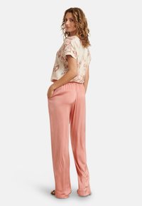 Lightweight cream blouse with pink abstract patterns, paired with flowy blush pink trousers featuring an elastic waistband and side pockets.