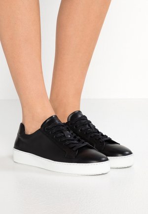 Sneakers in pelle nera con punta arrotondata, suola piatta in gomma bianca e lacci neri abbinati. Tessuto liscio con dettagli di cucitura sottili.