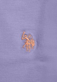 Small embroidered design of two people on bicycles in light orange thread on lavender fabric.