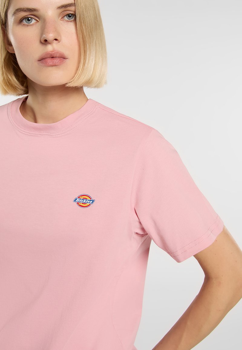 Lichtroze katoenen T-shirt met korte mouwen en een ronde hals, met een klein meerkleurig Dickies-logo op de borst.
