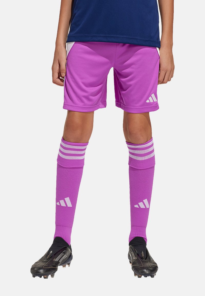 Roze voetbalshorts en bijpassende roze kniekousen, beide met witte Adidas-logo's, gecombineerd met zwarte voetbalschoenen.