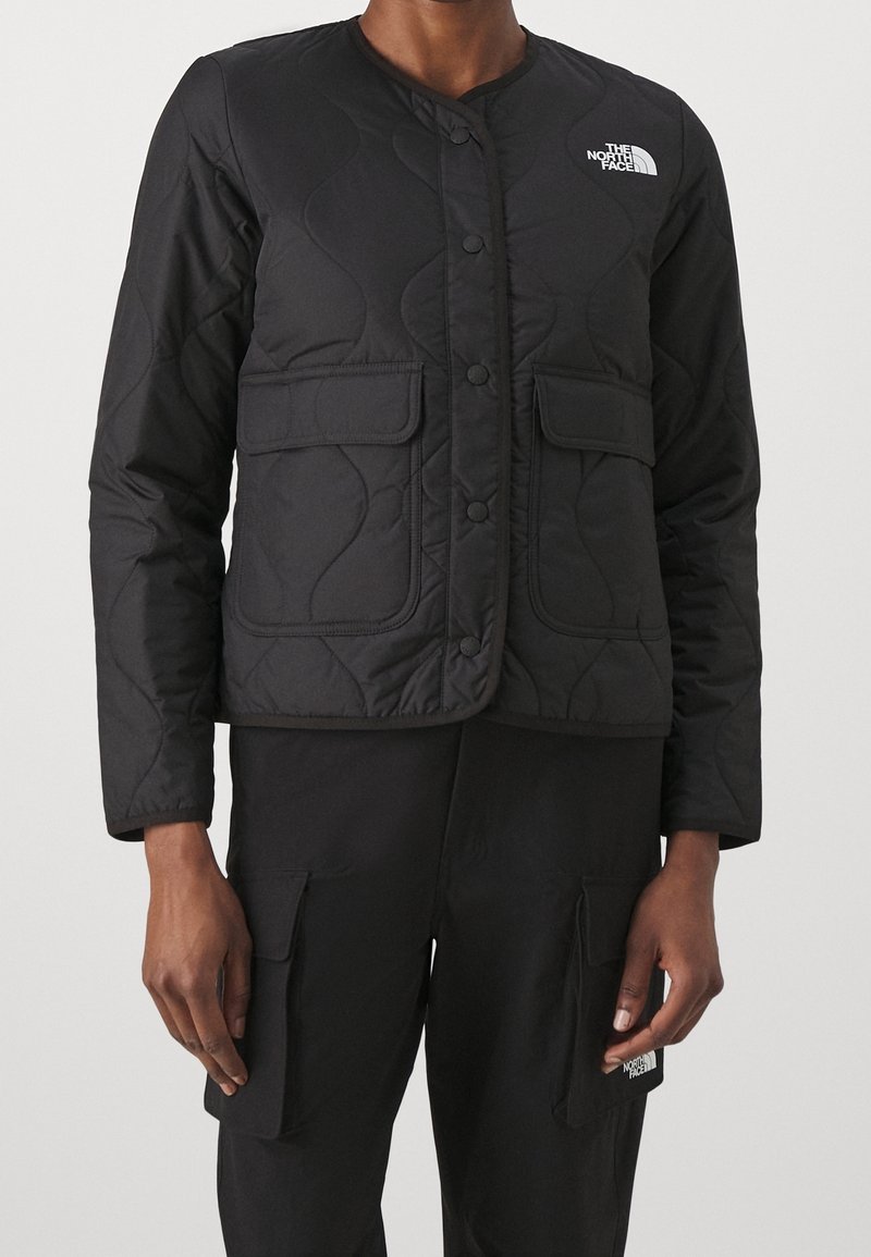 Černá prošívaná bunda s kulatým výstřihem, patentkami, dvěma předními kapsami a logem "The North Face" na levé horní straně.