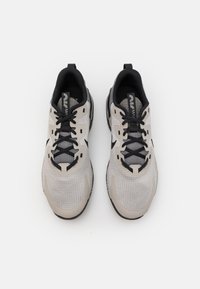 Hellgraue Laufschuhe mit einer strukturierten Oberseite, schwarzen Schnürsenkeln und einer schwarzen Außensohle. Verfügt über eine Schlaufe und Mesh-Einsätze für Atmungsaktivität.
