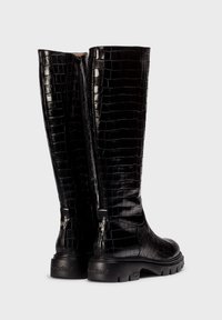 Botas negras hasta la rodilla hechas de cuero con estampado de cocodrilo, que presentan un acabado texturizado, cremalleras laterales y suelas de goma con detalle del logotipo.