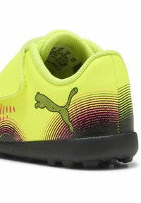 Pantofii sintetici galbeni neon cu talpă neagră, având un model în gradient roz și logo-ul Puma. Partea superioară texturată cu guler căptușit.