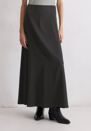 Lange schwarze Rock aus weichem, fließendem Stoff mit glatter Textur, featuring eine hohe Taille und eine leicht ausgestellte Silhouette, kombiniert mit schwarzen Stiefeln.