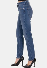 Jeans in denim blu slim-fit con vita alta, gamba dritta e cuciture a contrasto. Abbinati a scarpe con tacco alto nere.