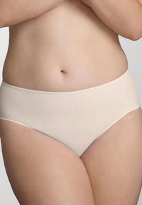 Slip beige chiaro senza cuciture, con una texture morbida, vita a media altezza e senza elastico visibile sulle gambe, progettati per il comfort e una vestibilità pulita.