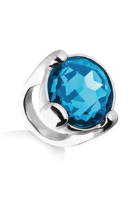 Bague en argent ornée d'une grande pierre précieuse bleue facettée, maintenue en place par des griffes lisses et courbes.