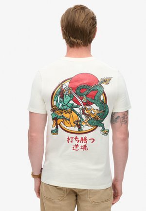 Camiseta de manga corta color crema con un gráfico de un guerrero y un dragón, frente a un sol rojo con texto estilizado en japonés.