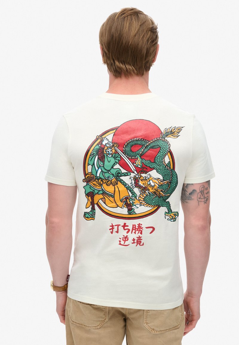 Kræmfædet kortærmet T-shirt i en beige farve med et grafisk design af en kriger og en drage, sat mod en rød sol med stiliseret tekst på japansk.