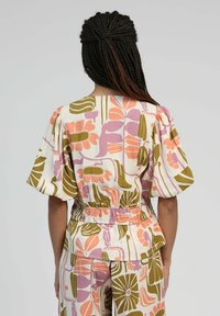 Haut à motif floral en crème, doté de manches bouffantes, d'une taille élastique et de teintes de rose, de vert et d'orange, avec une coupe décontractée.