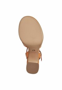 Tan heeled sandal with a smooth sole, adjustable ankle strap, and textured insole featuring the brand name. Sole has ribbed grip pattern.