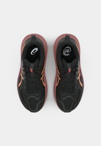 Baskets de sport noires avec une tige en mesh et des accents maroon. Comprennent des lacets, un design orange sur les côtés et une semelle rembourrée. Construction légère.