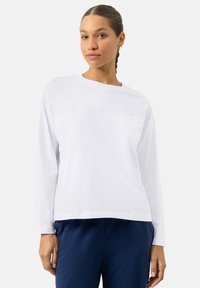 Witte lange mouw katoenen t-shirt met een ronde halslijn en een subtiel lichtroze smiley gezicht logo op de borst.