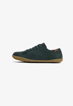 Dark green suede sneaker with six eyelets, rounded toe, and a rubber sole. Features a small brown leather accent at the heel.