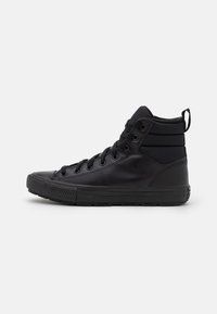 Black high-top sneakers featuring a smooth leather exterior, textured accents, round toe, lace-up design, and a padded collar for support.