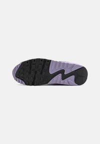 Nike potplat tenisice s crnom gumenom podlogom, teksturiranim uzorkom za prianjanje, i ljubičastim srednjim dijelom s valovitim dizajnom i točkicama.
