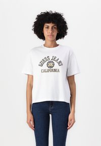 Bílá bavlněná tričko s krátkým rukávem, s kulatým výstřihem a logem "GUESS JEANS CALIFORNIA" v modré a žluté barvě na přední straně.