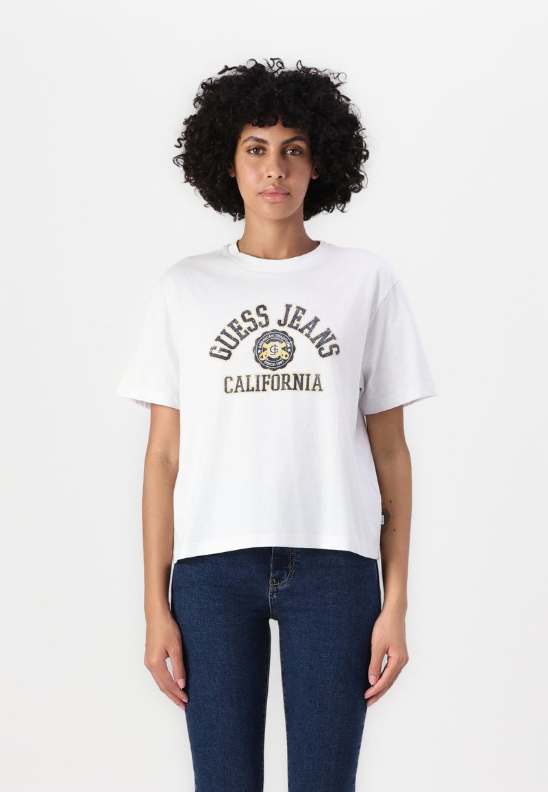Bílá bavlněná tričko s krátkým rukávem, s kulatým výstřihem a logem "GUESS JEANS CALIFORNIA" v modré a žluté barvě na přední straně.