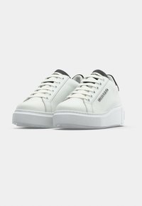 Baskets à plateforme blanches avec des languettes de talon noires et le logo "Valentino" sur le côté, vues de face sur un fond blanc.