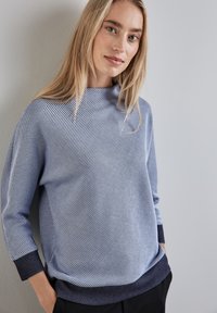 Maglione a righe blu chiaro con collo alto, maniche lunghe e polsini blu scuro. Tessuto morbido con motivi diagonali e una vestibilità comoda.