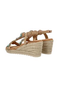 Sandalias de cuña beige con acentos decorativos en turquesa y plata, que presentan una suela de yute trenzado y un talón cerrado con una correa ajustable.
