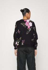 Black sweatshirt with a floral design in pink and green, featuring a slightly cropped fit, long sleeves, and ribbed cuffs and hem.
