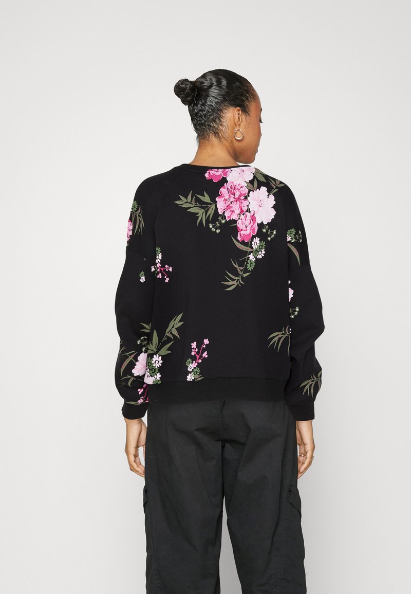 Sweatshirt noir avec un motif floral en rose et vert, présentant une coupe légèrement cropped, des manches longues, ainsi que des poignets et un ourlet côtelés.