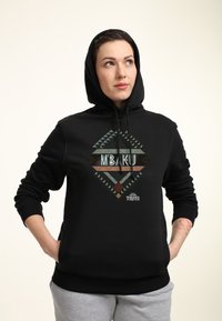 Sudadera negra de algodón con un diseño gráfico geométrico en teal, verde y marrón, que presenta las palabras "MBAKU" y el logo "Wakanda Forever".