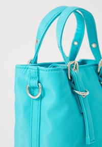 Borsa turchese realizzata in tessuto testurizzato. Presenta hardware argentato, manici doppi e parte superiore arricciata con chiusura a coulisse.