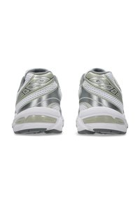 Scarpe sportive grigie e argento con tomaia in rete, collare imbottito e suola bianca con un'unità di ammortizzazione visibile.