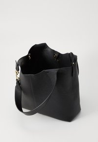 Black leather tote bag with a textured finish. Features a wide opening, rounded edges, and gold hardware accents. Adjustable strap included.